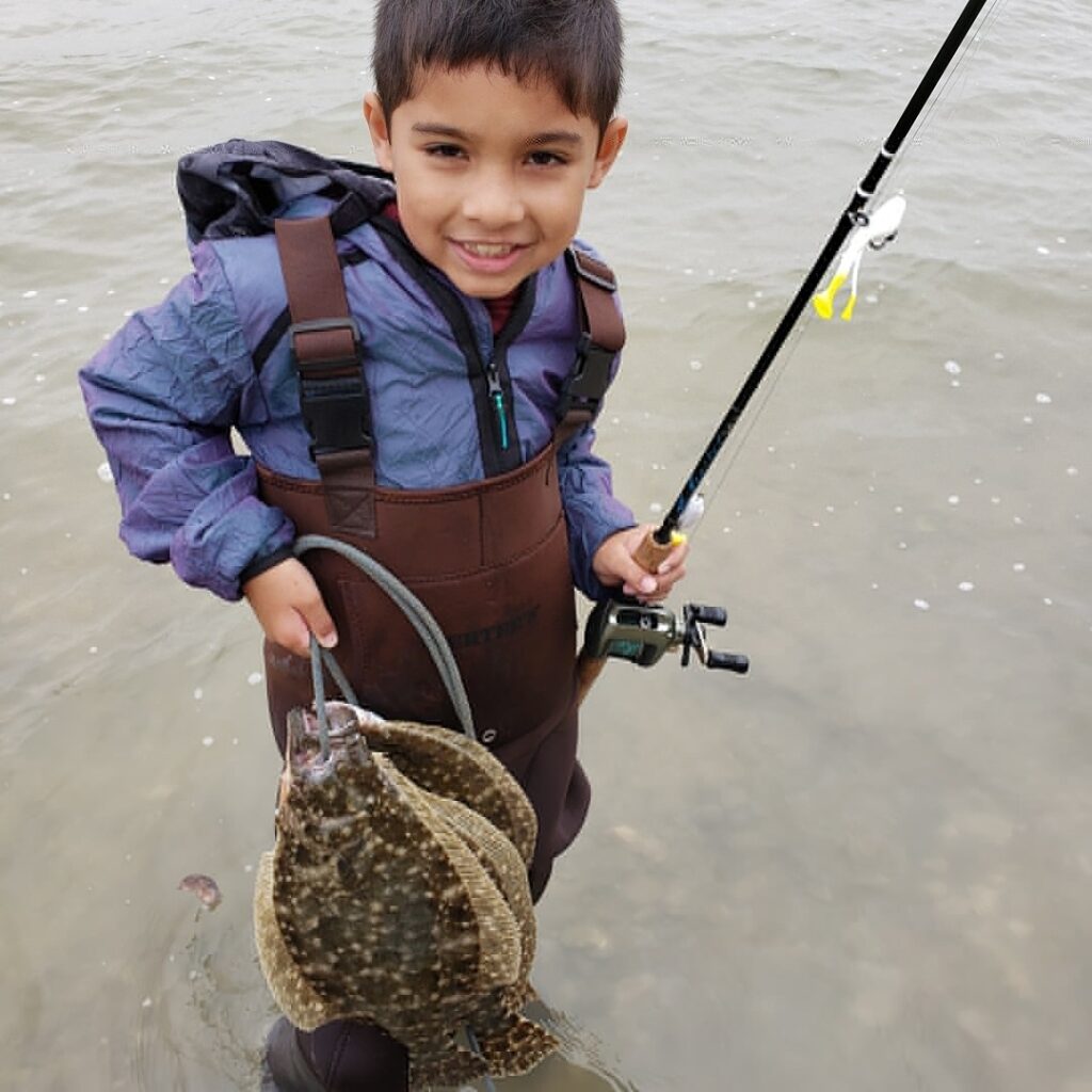 A young fisherman with a stringer of flounder.