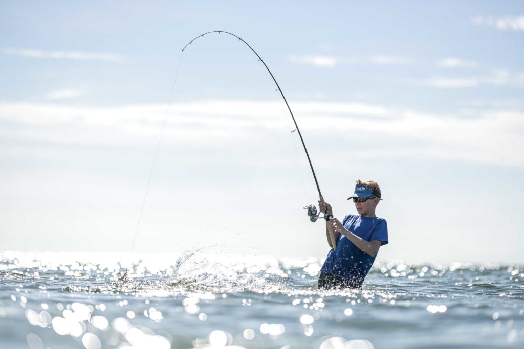 Close up of spinning with the fishing reel in the hand, fishing hook on the  line with the bait in the left hand against the background of the water.  6533276 Stock Photo
