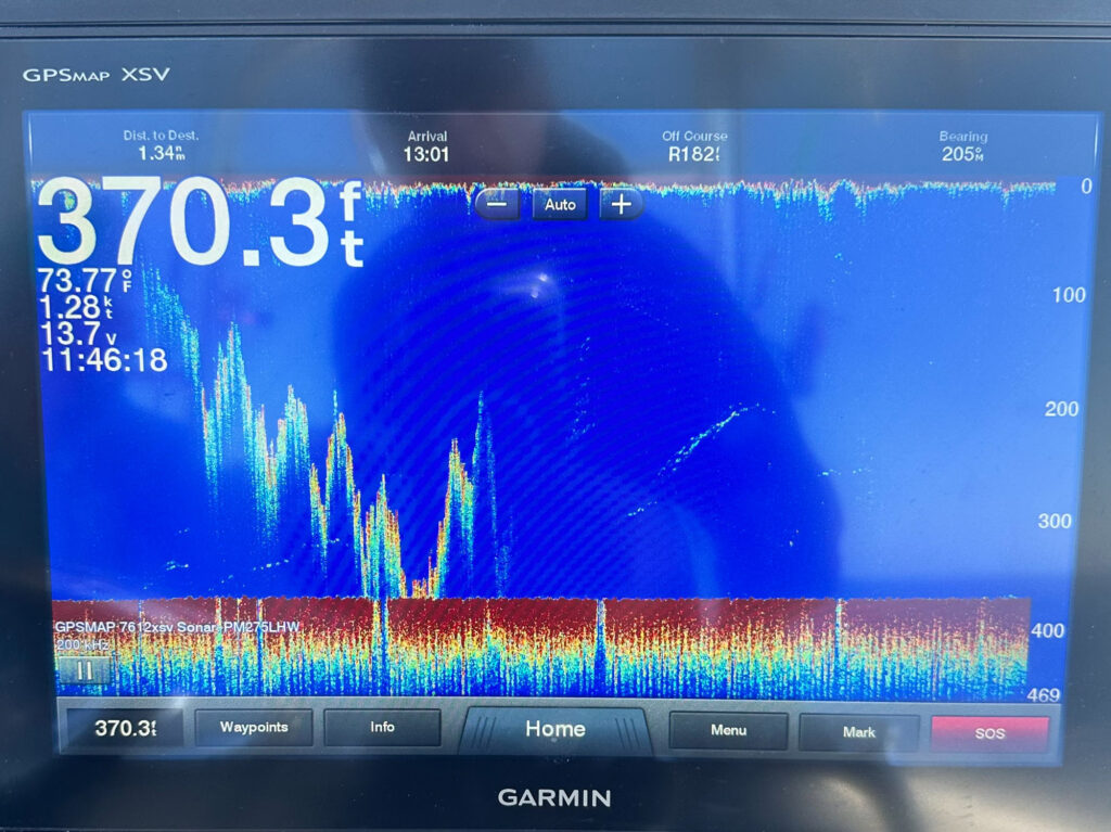 A Garmin fish finder screen shows activity beneath the boat.