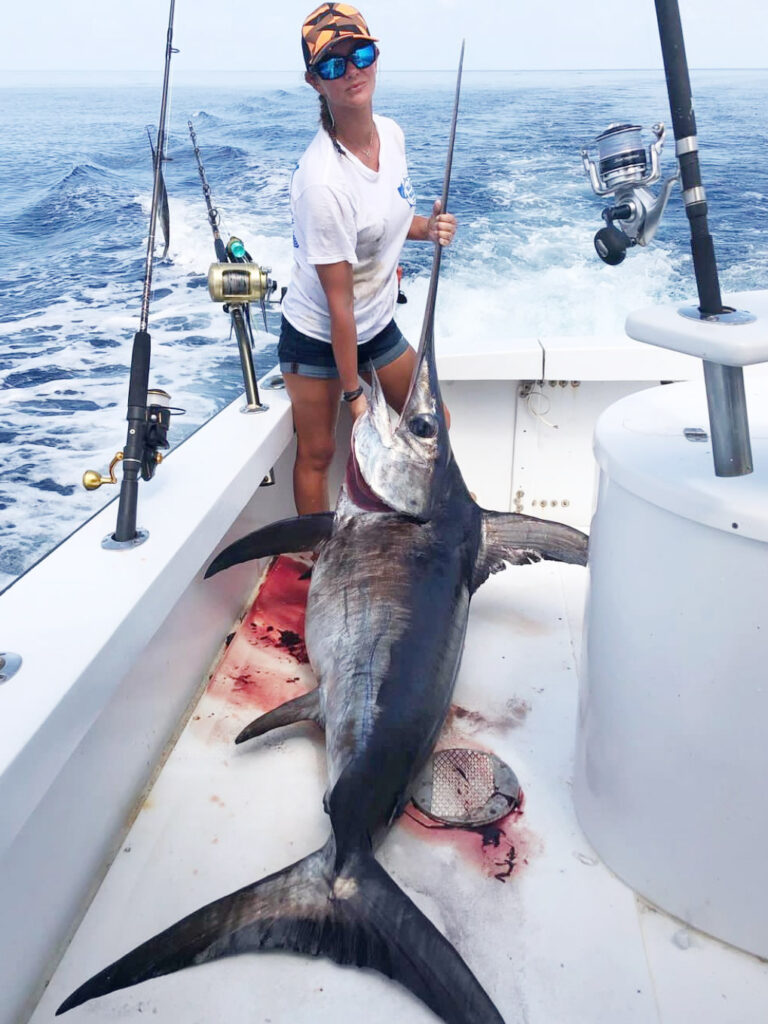 Capt. Quinlyn Haddon holds a freshly caught swordfish on the deck of her boat.