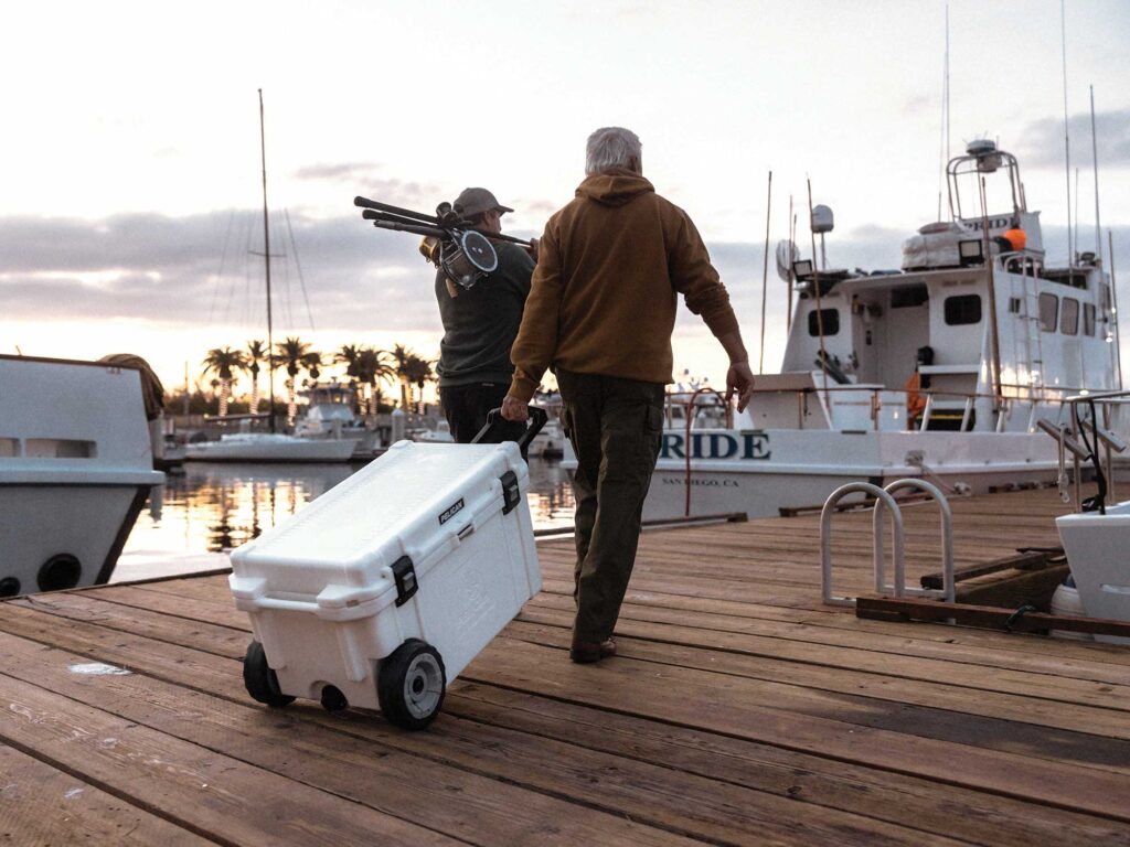 Anglers carrying cooler down dock